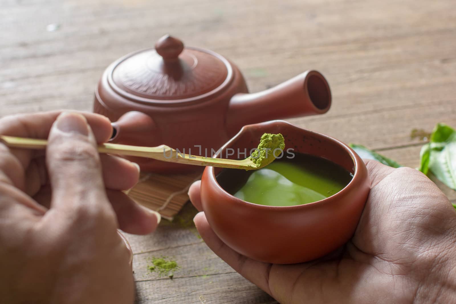Matcha Green Tea and Japanese tea set. Ceramic teapot and a steaming cup on wooden background.