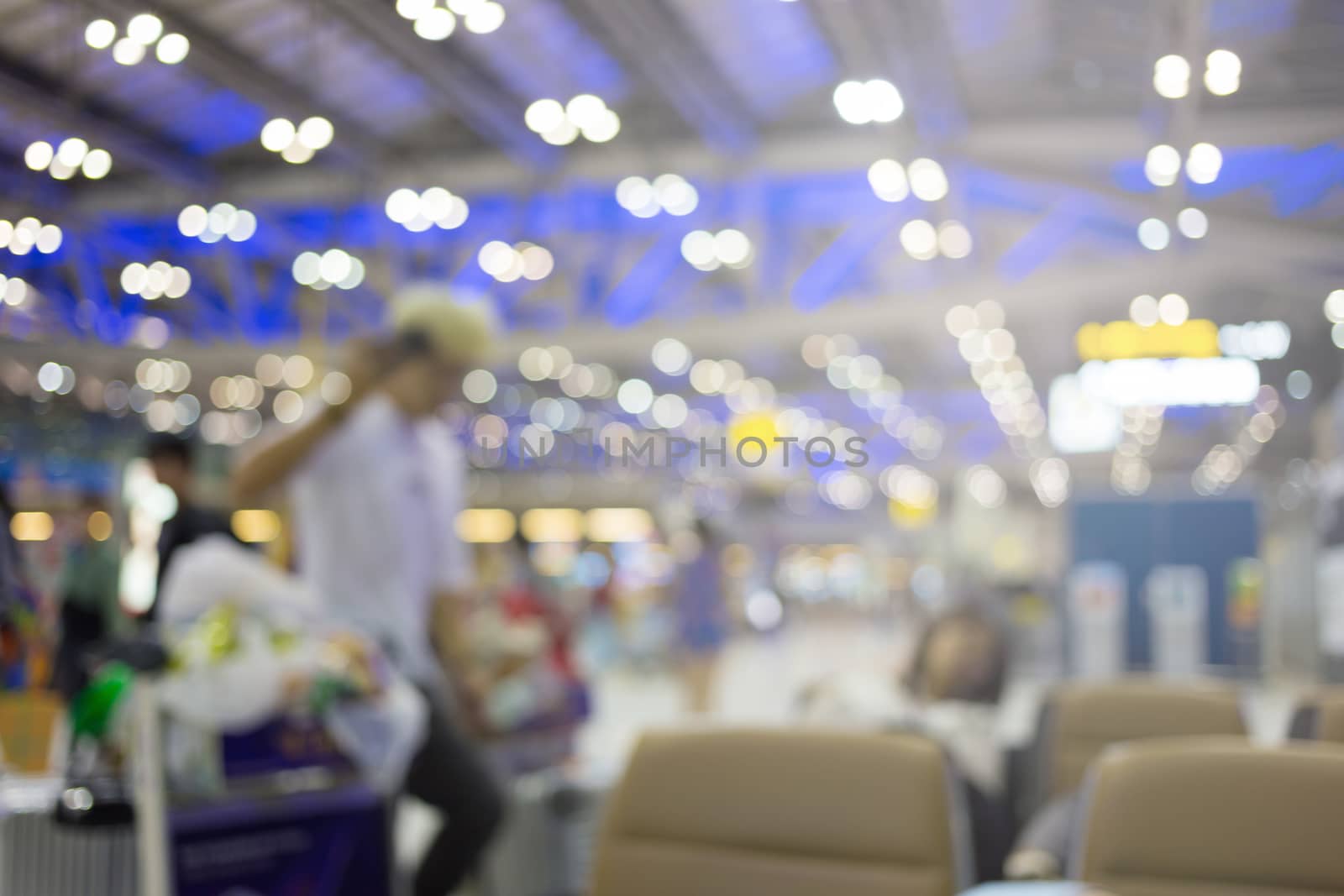 blurred image of travelers smart people walking with a luggag at airport terminal with crowd of travelling people in background. Traveling concept.
