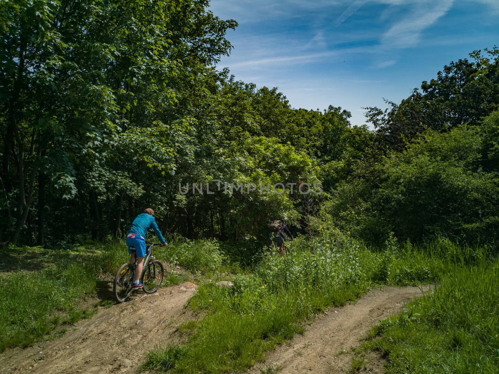Two mens at edge of hill ride downhill in park by Wierzchu