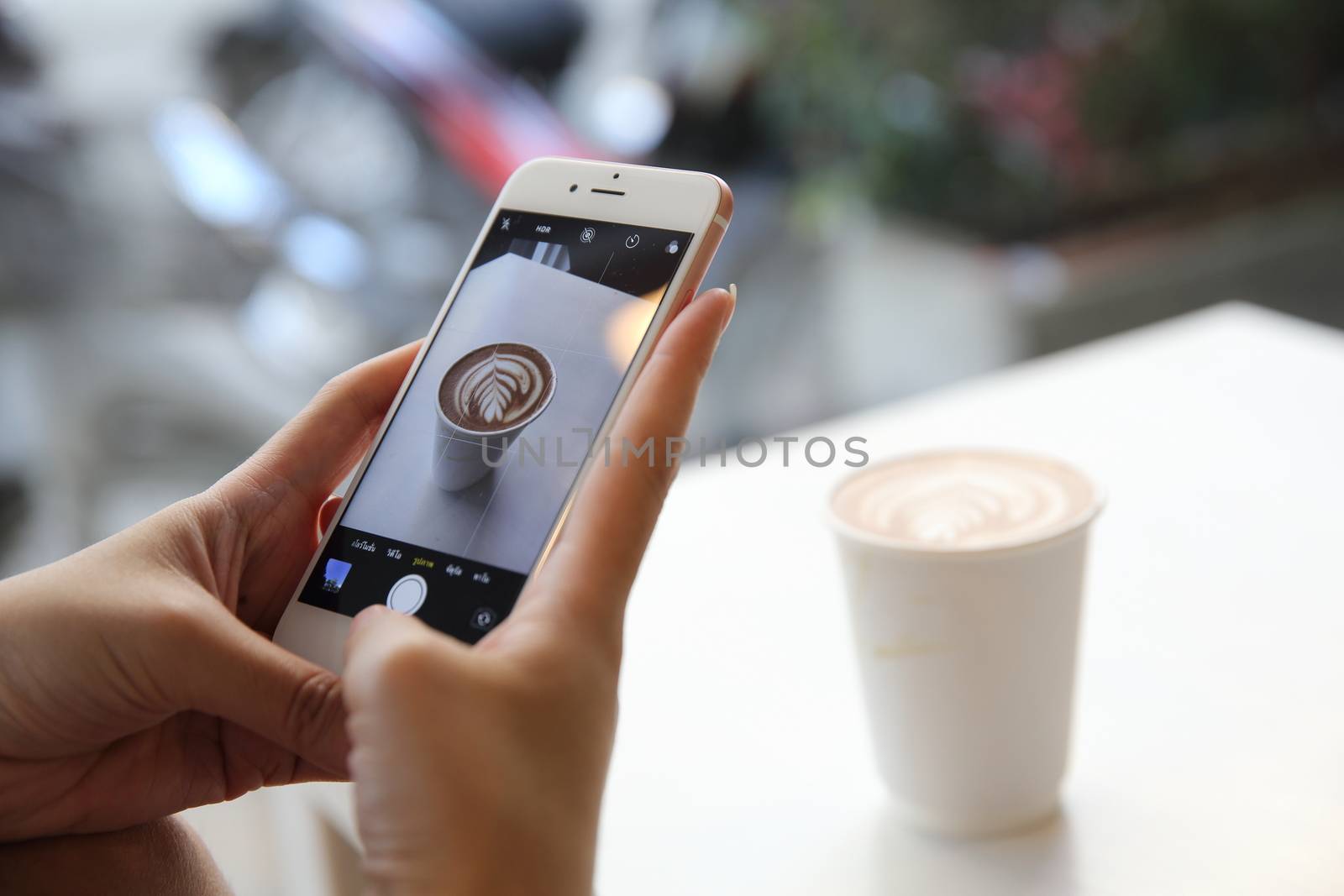 Young woman taking coffee picture with smartphone by piyato