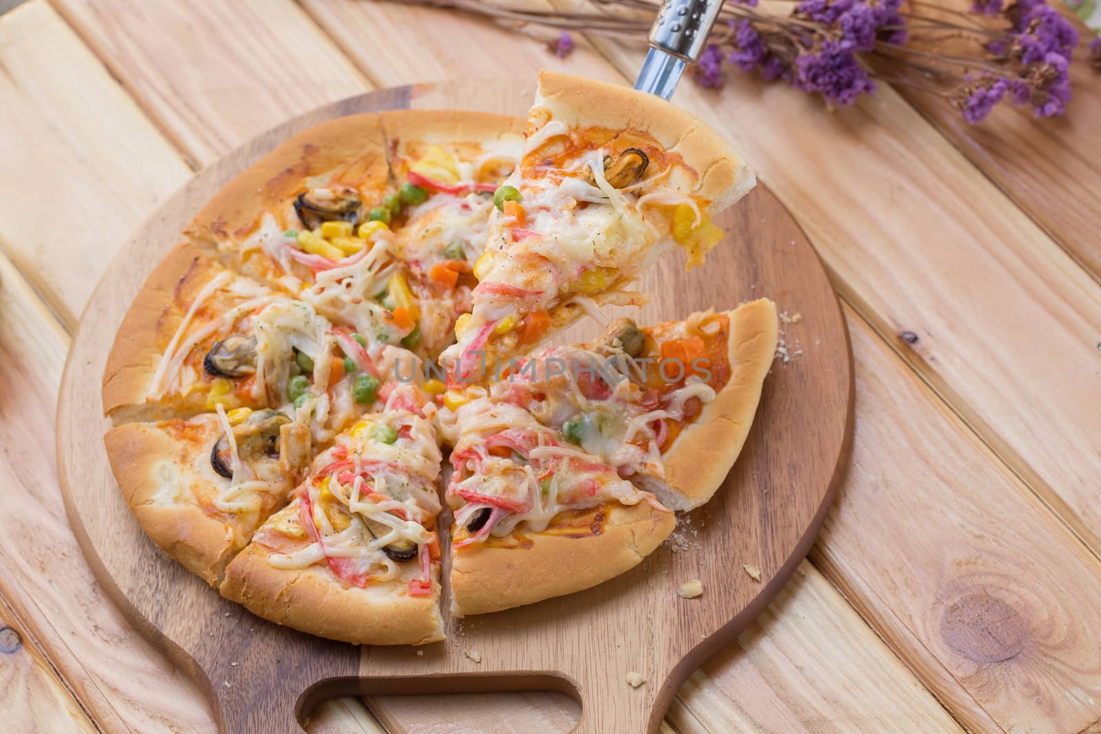 Close up of tasty homemade seafood topped pizza fusion food style on wooden tray.