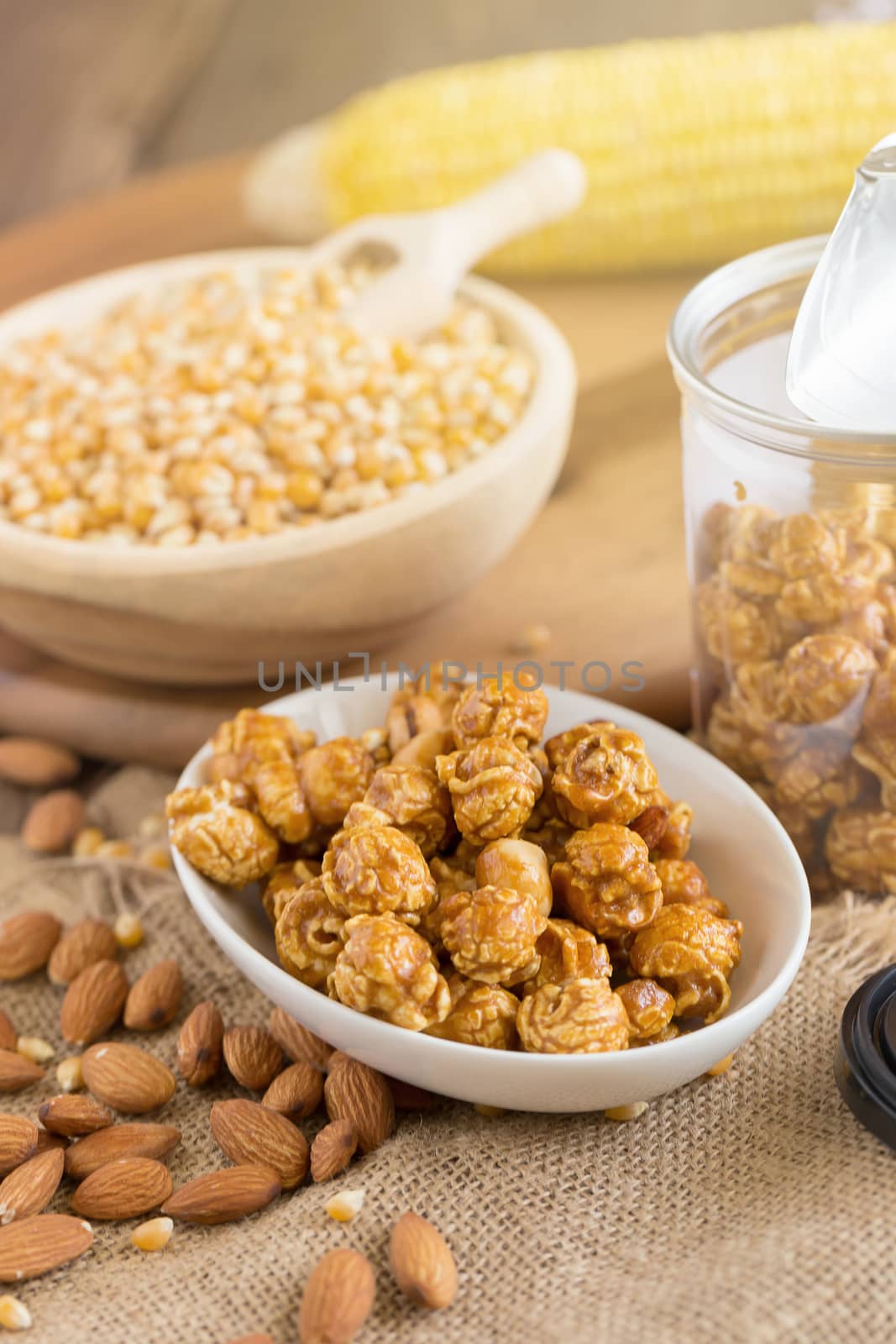 Corn kernels in wooden plates and popcorn with Caramel and almond cream on wooden table.