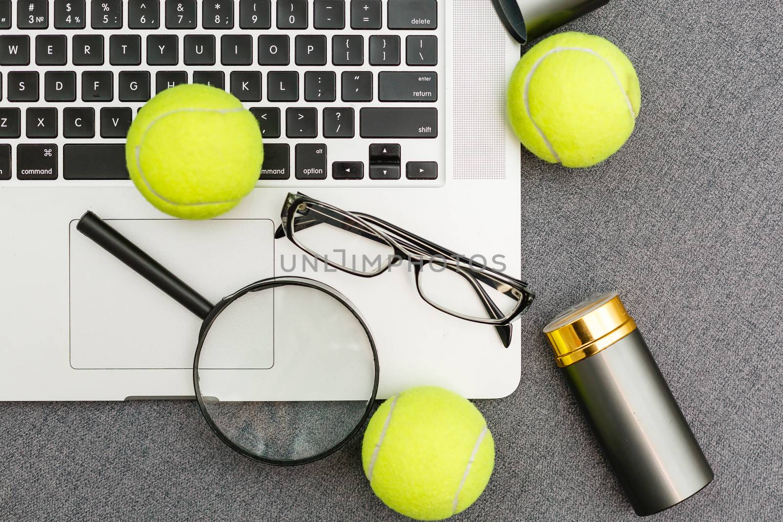 Top view of laptop, Sports Equipment, Tennis ball, Shuttlecock, glasses aon the Sports administration gray table.Business concept. by Andelov13