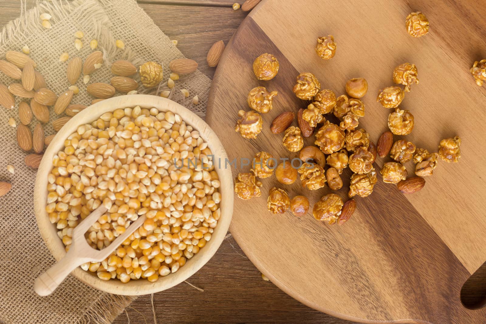 Corn kernels in wooden plates and popcorn with Caramel and almond cream on wooden table.