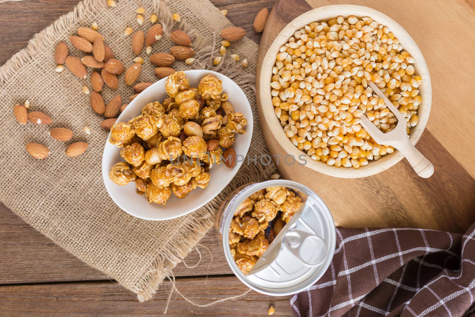 Corn kernels in wooden plates and popcorn with Caramel and almond cream on wooden table.