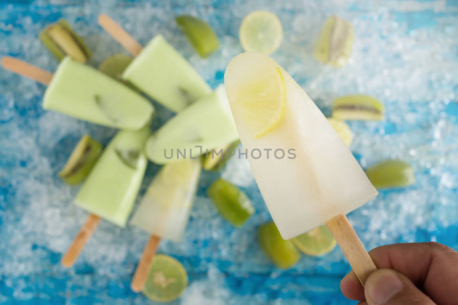 Crushed ice cubes and lemon, kiwi, homemade ice cream on vintage blue wooden table. Top view.