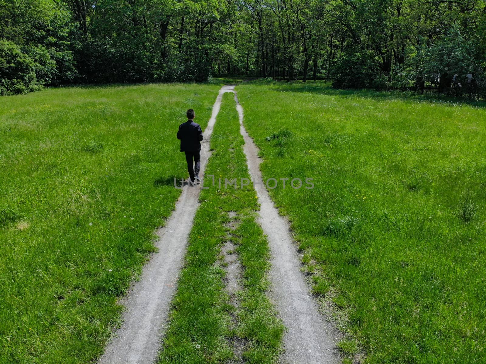 Man on double path at green clearing with trees around