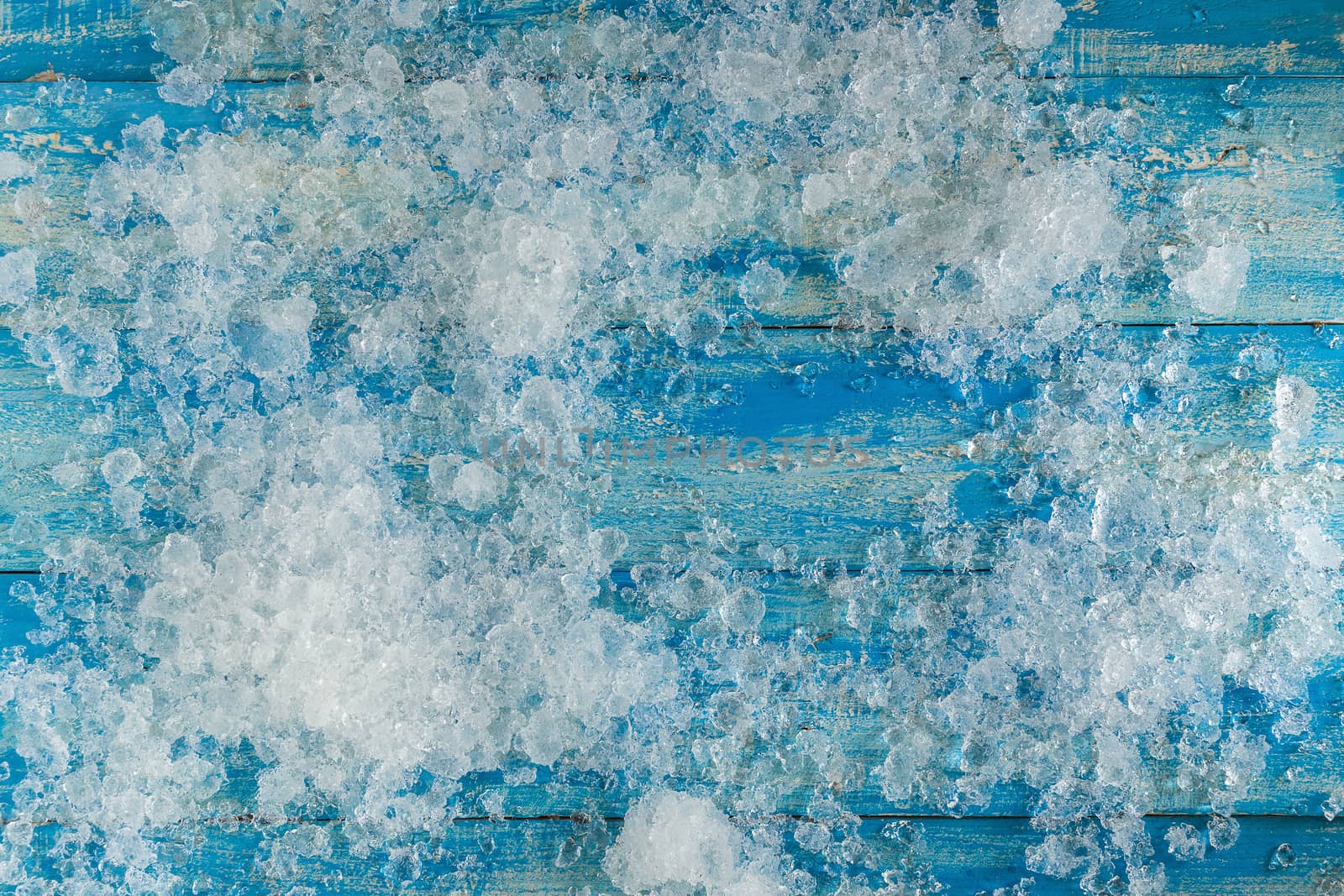 Crushed ice cubes on vintage blue wooden table. Top view.