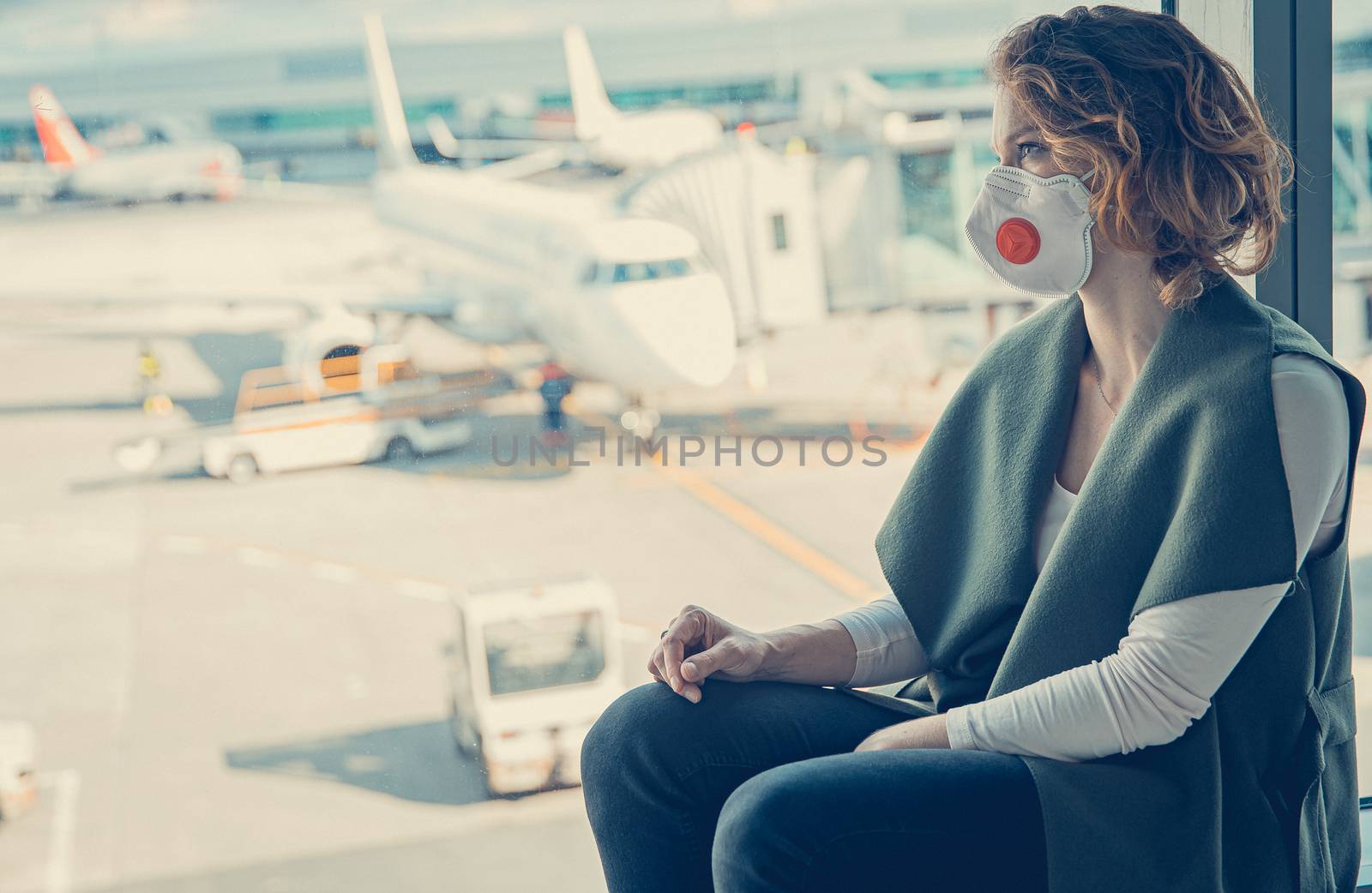 woman waiting for check-in in the airport lobby. The use of respirators for protection against viruses by Edophoto