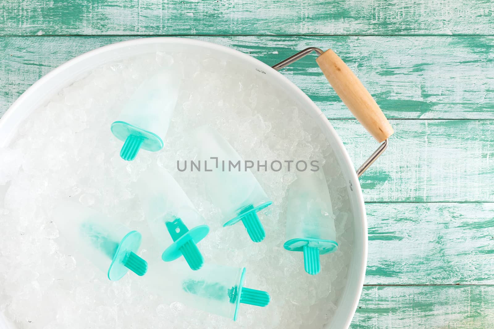 Ice crushed on green wooden background and ice in a white tray.