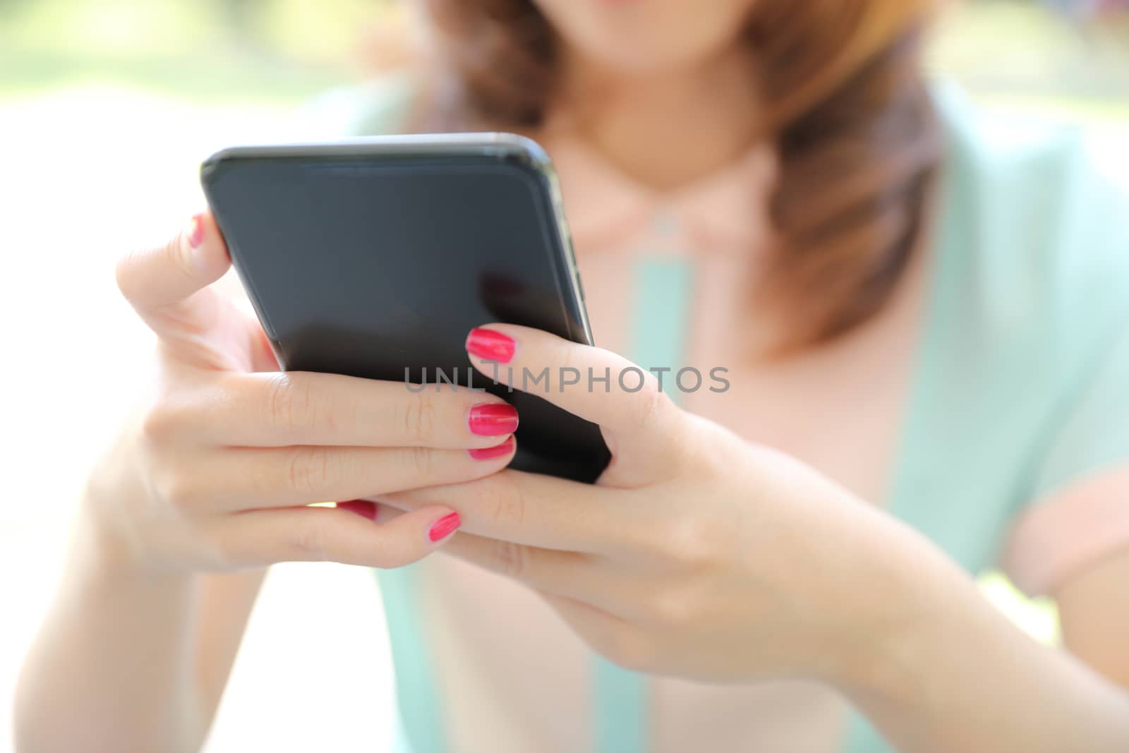 Female hand with smartphone trading stock online in coffee shop  by piyato