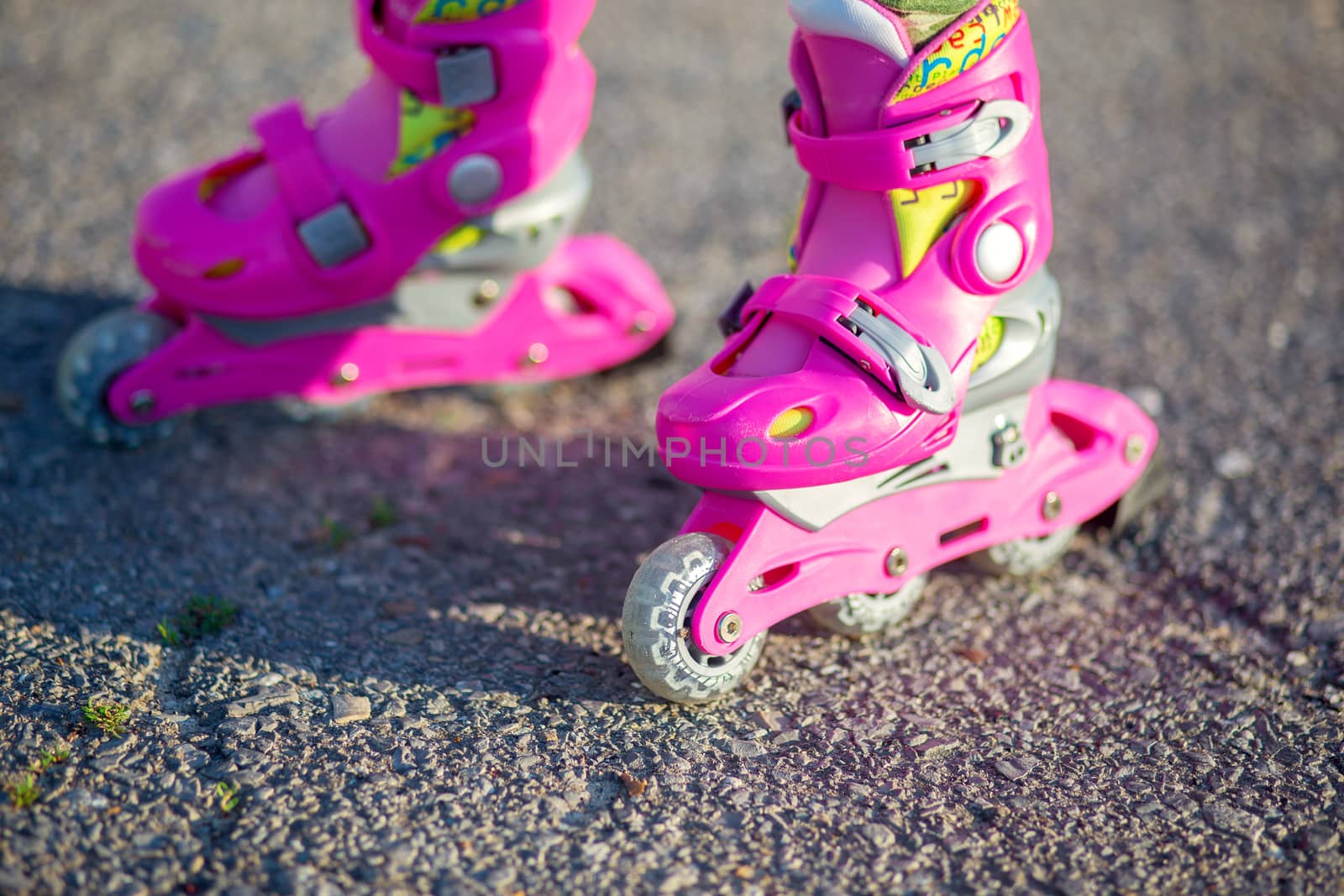 Childrens feet in pink childrens rollers close-up. Roller skates for outdoor sports. Healthy lifestyle baby