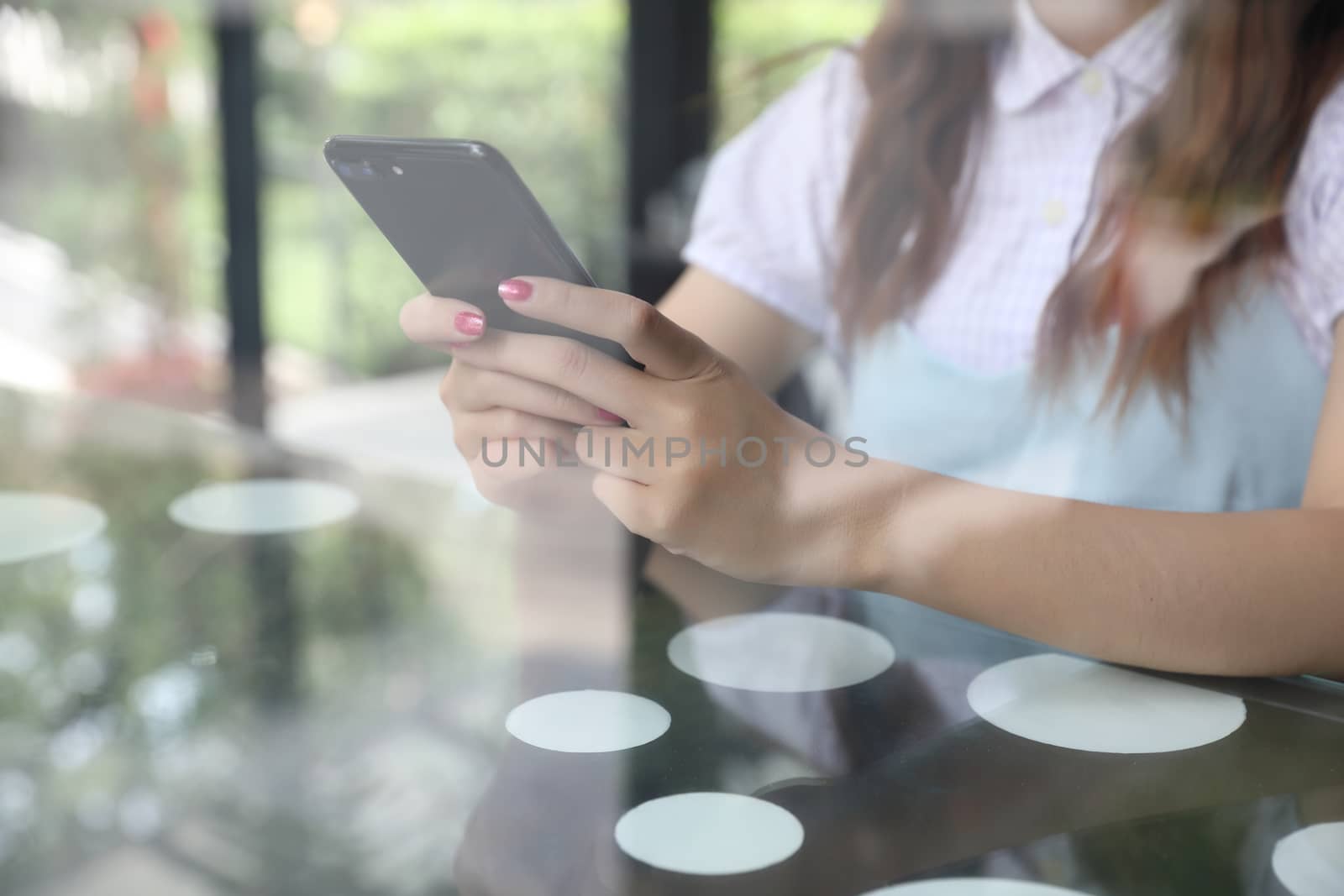 Female hand with smartphone trading stock online in coffee shop  by piyato