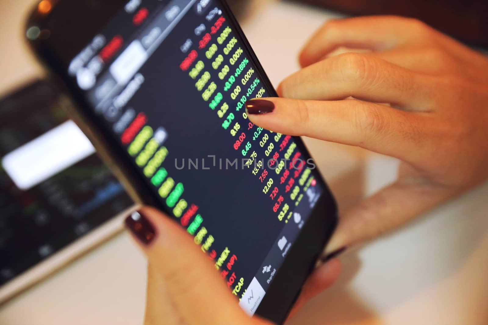 Female hand with smartphone trading stock online in coffee shop , Business concept