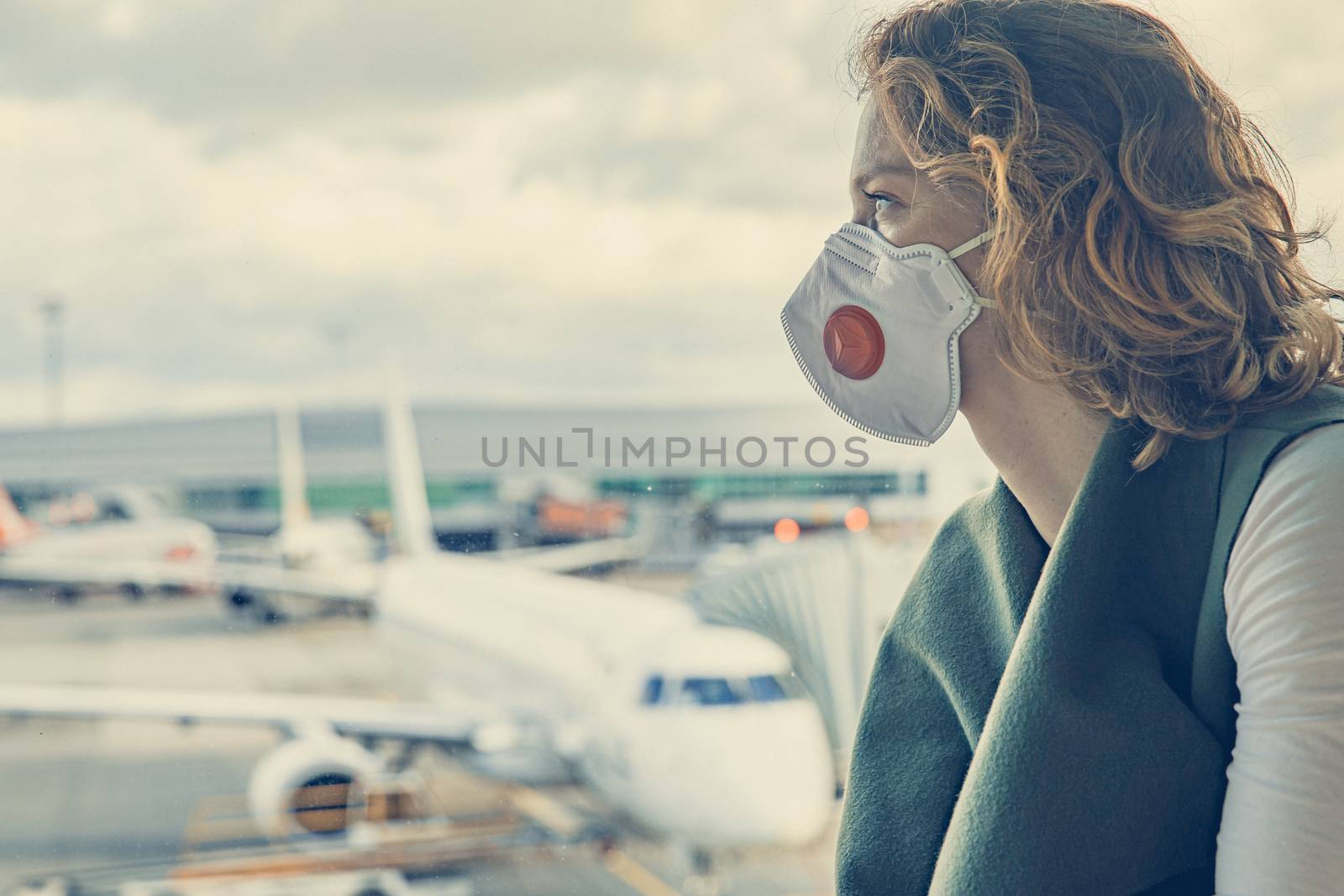 woman at airport with mask on head for protection against virus. trapped at the airport because of coronavirus by Edophoto