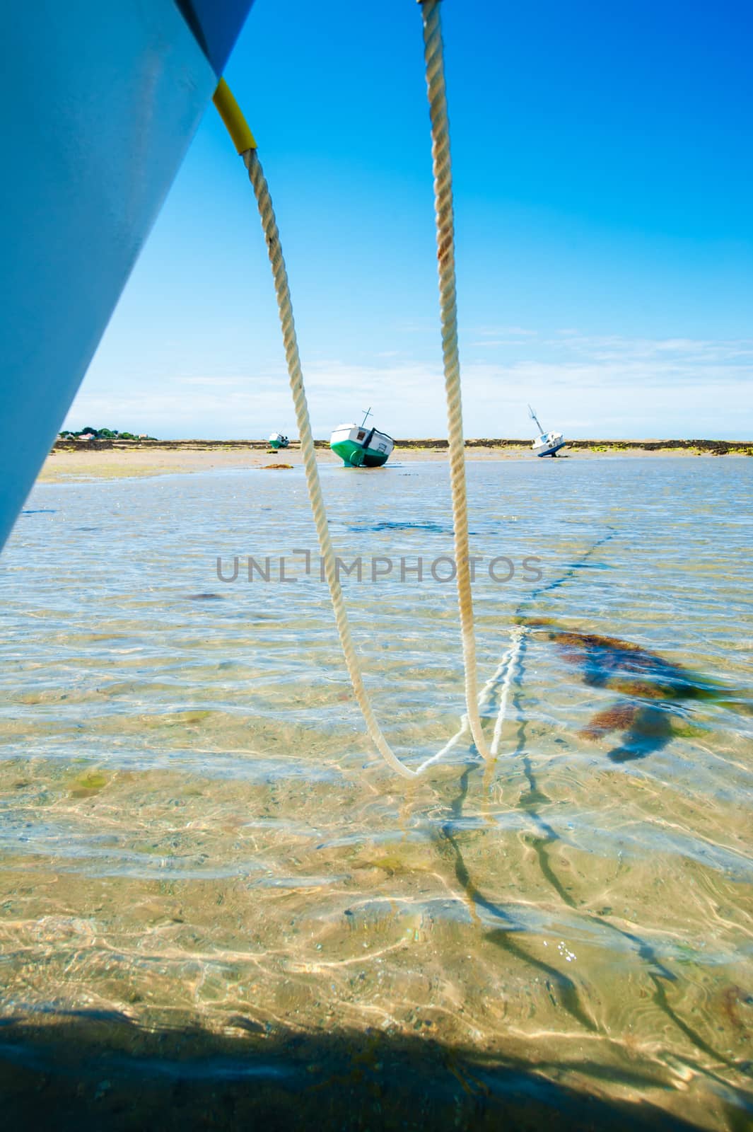 view on a boat between the anchor line of another boat which are anchored on the beach