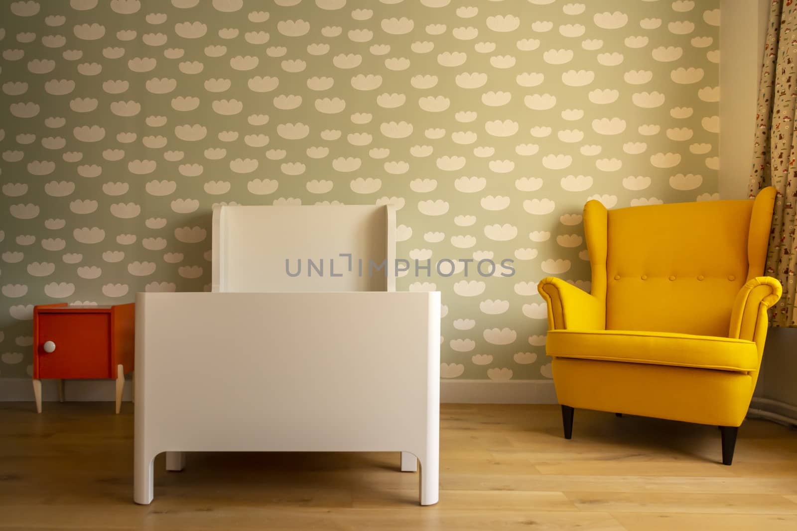 Toddler boy's sleeping room, with cloud pattern on wall, vintage chair, wooden floor and orange bedside table. Vintage look.