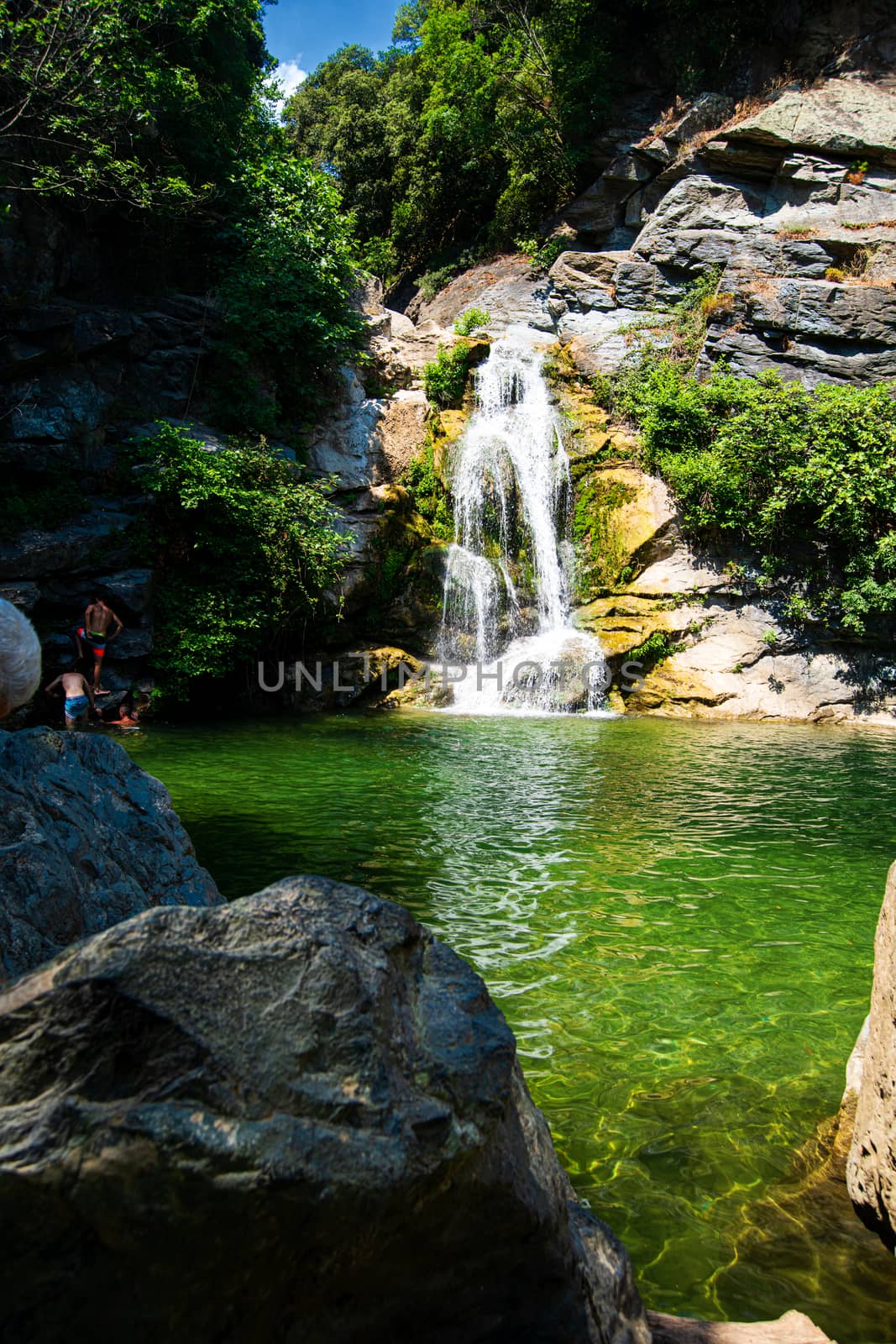 small waterfall in a forest on the isle of Corsica in France where people can swim during summertime