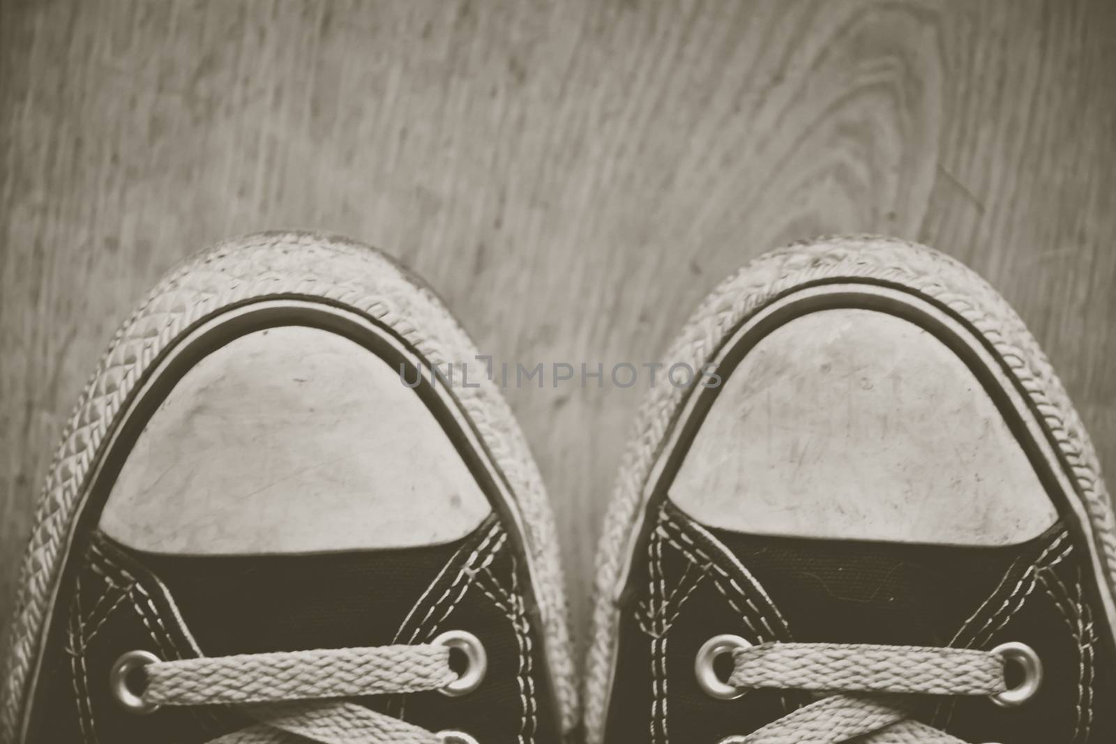 orn out converse Chuck Taylor All-Star sneakers tips, with black fabric, on wooden floor. Creative edit. by kb79