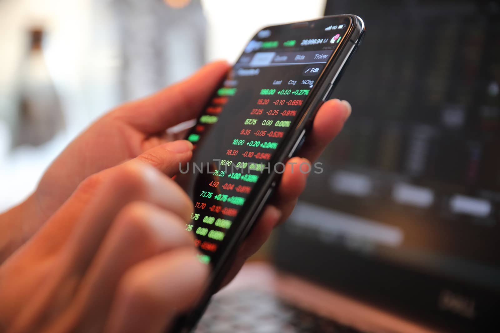 Female hand with smartphone trading stock online in coffee shop  by piyato