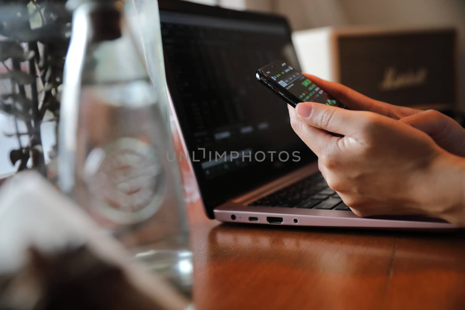 Female hand with smartphone trading stock online in coffee shop , Business concept