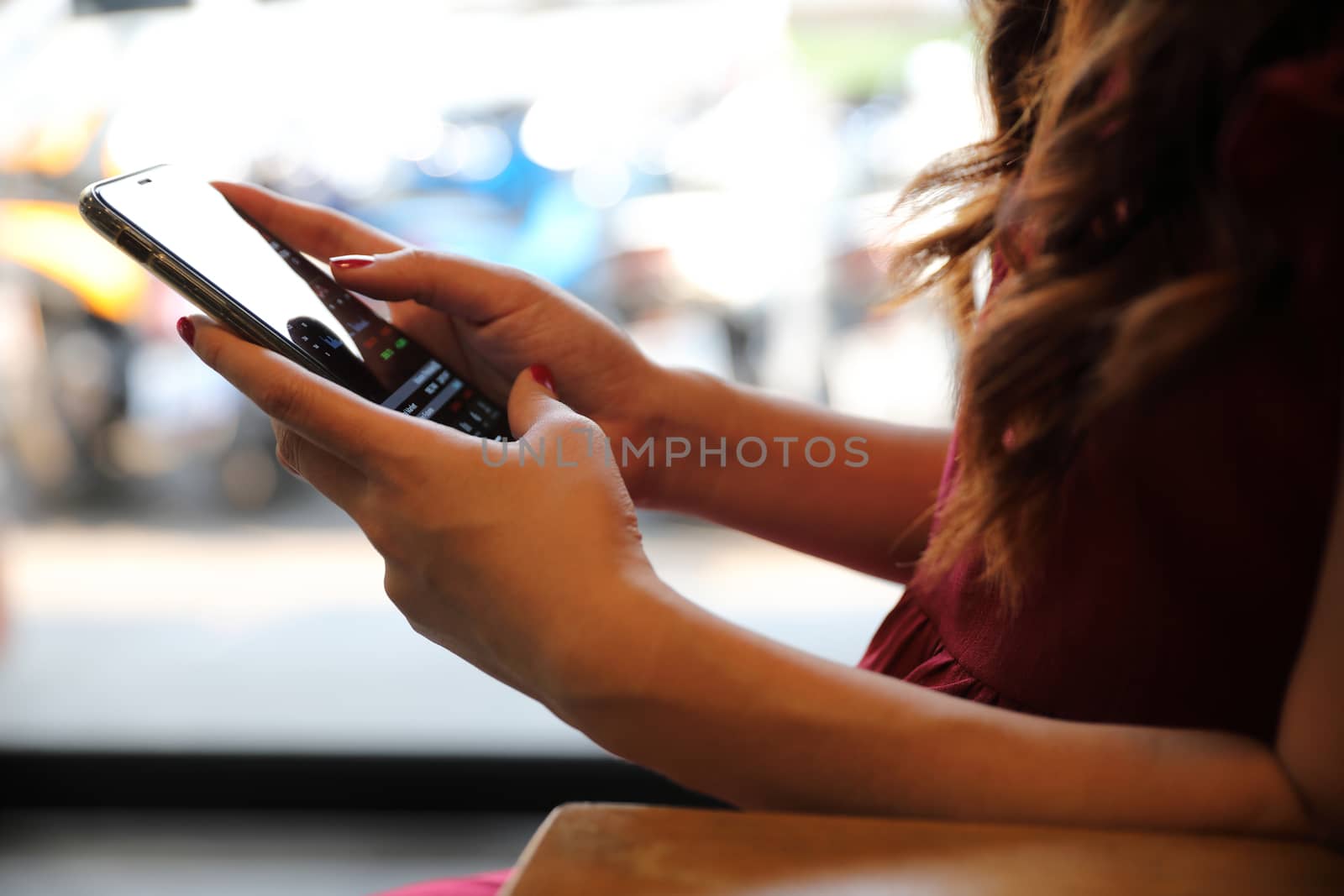 Female hand with smartphone trading stock online in coffee shop , Business concept