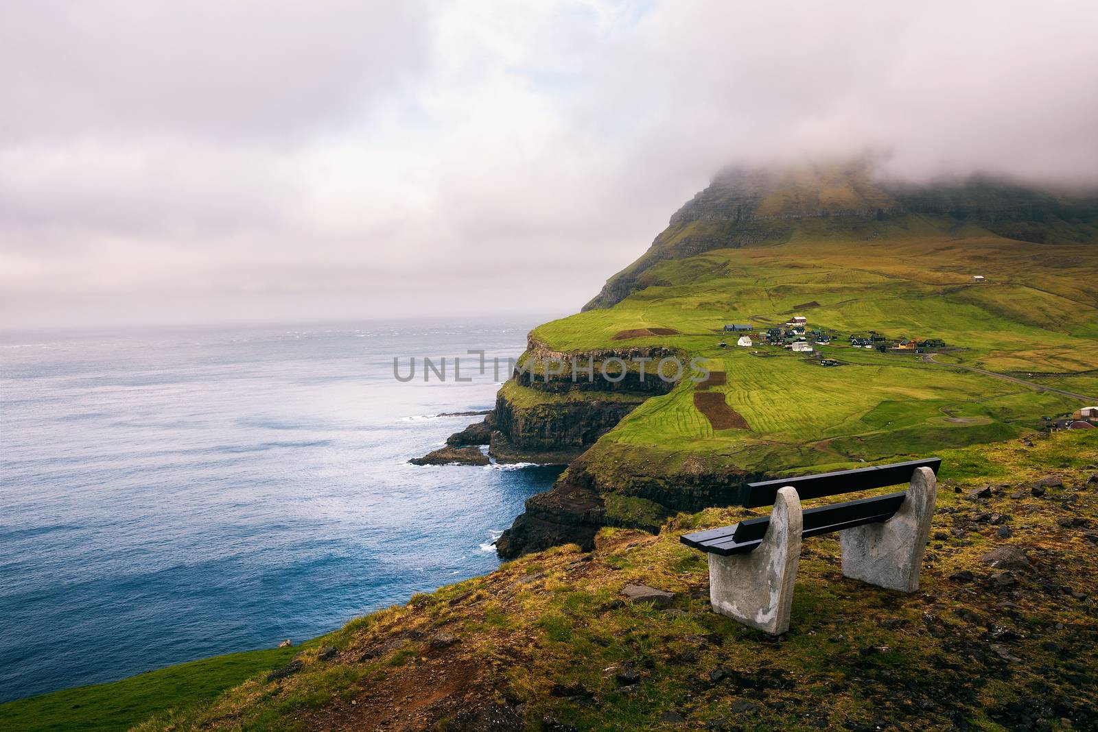 Bench above the village of Gasadalur with views over beautiful faroese scenery and Atlantic Ocean on the island of Vagar, Faroe Islands, Denmark.