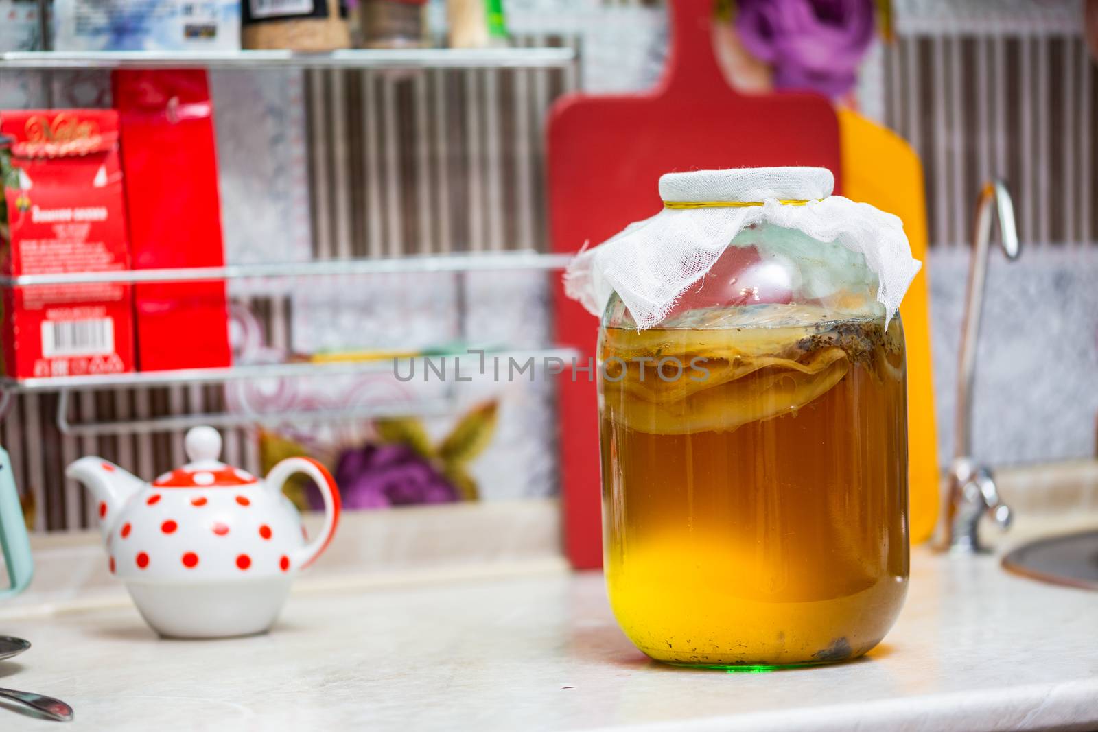 Homemade Kombucha Tea in glass jar on kitchen table - close-up with selective focus