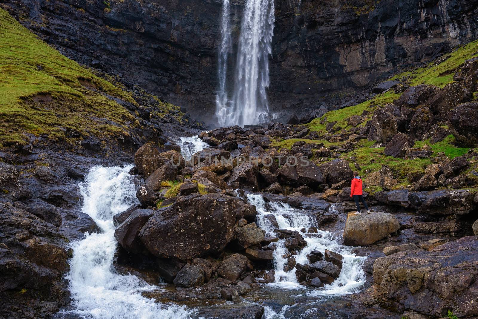Tourist standing at the Fossa Waterfall on island Bordoy in the Faroe Islands, Denmark