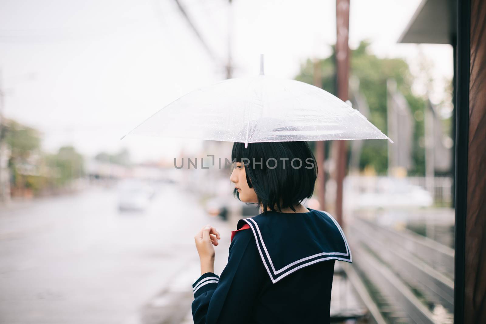 Portrait of Asian school girl walking with umbrella at  nature w by piyato