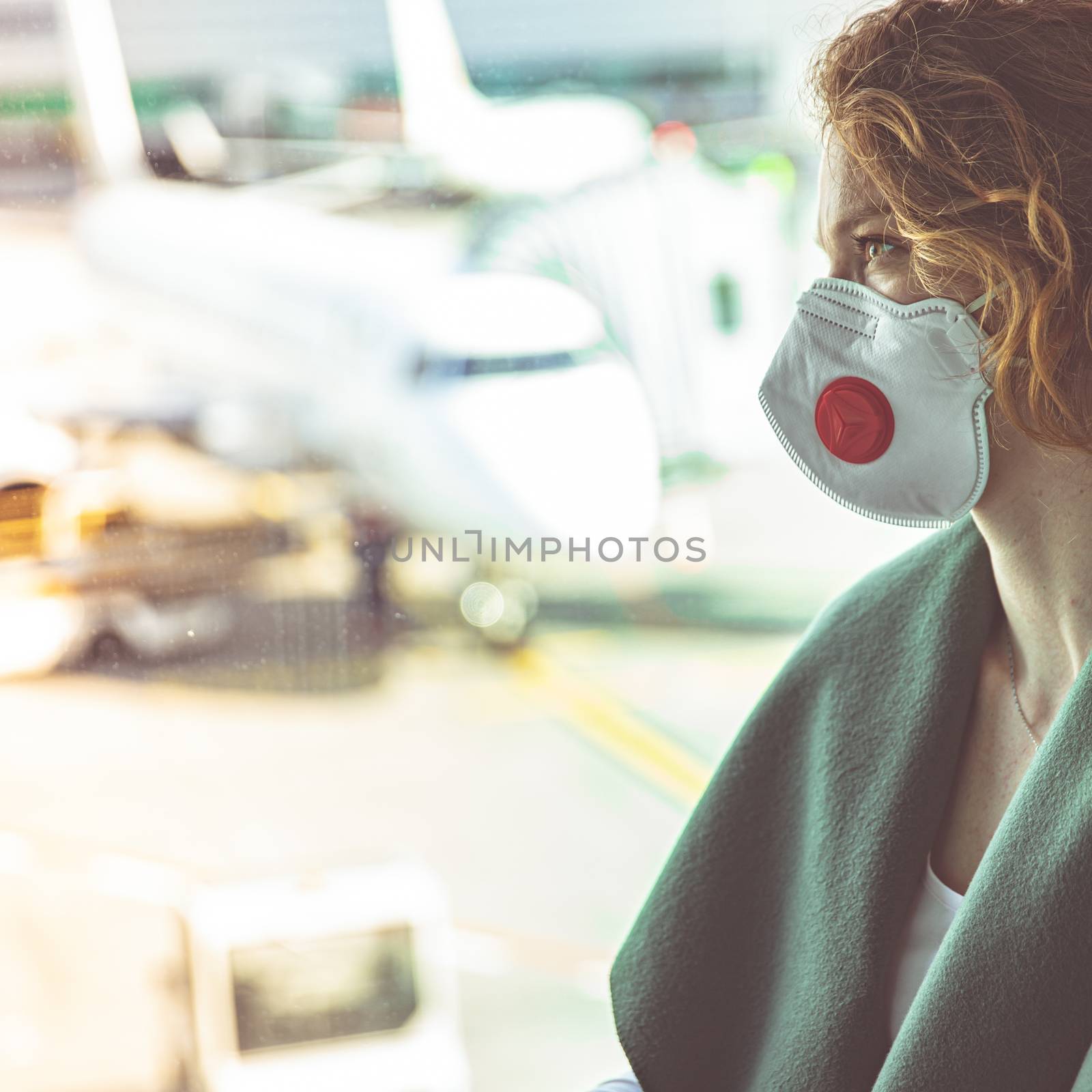 woman at airport with mask on head for protection against virus. Airport measures associated with coronavirus by Edophoto