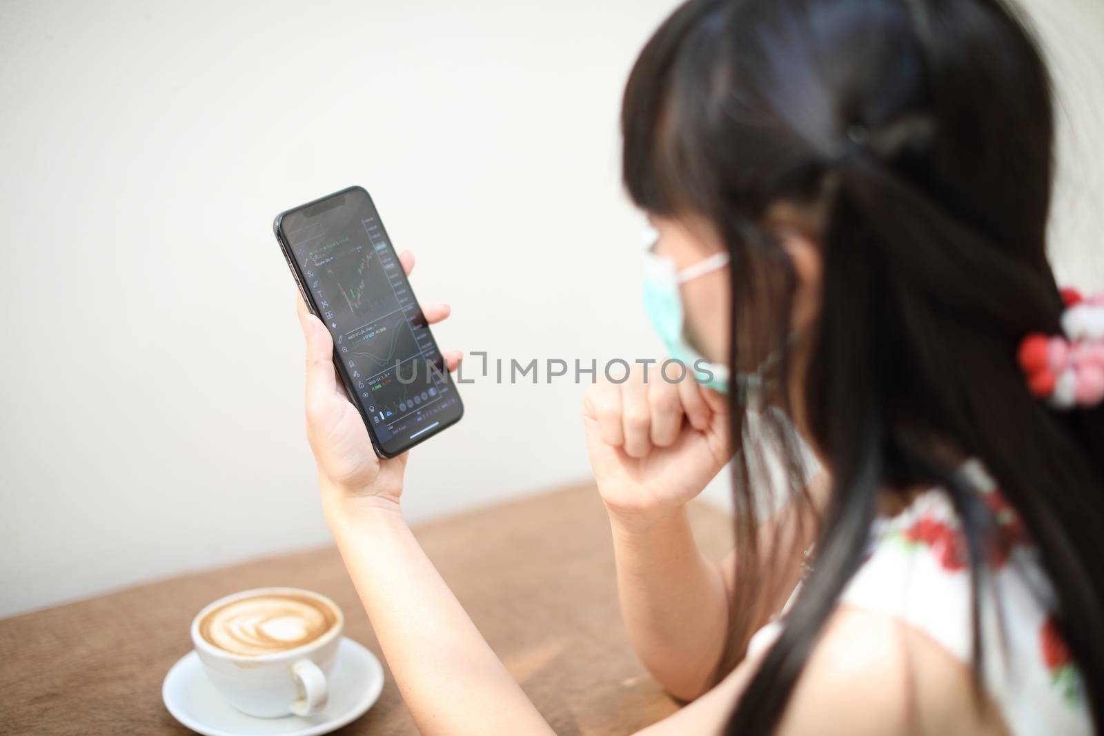 Portrait Female with mask using smartphone trading stock online  by piyato