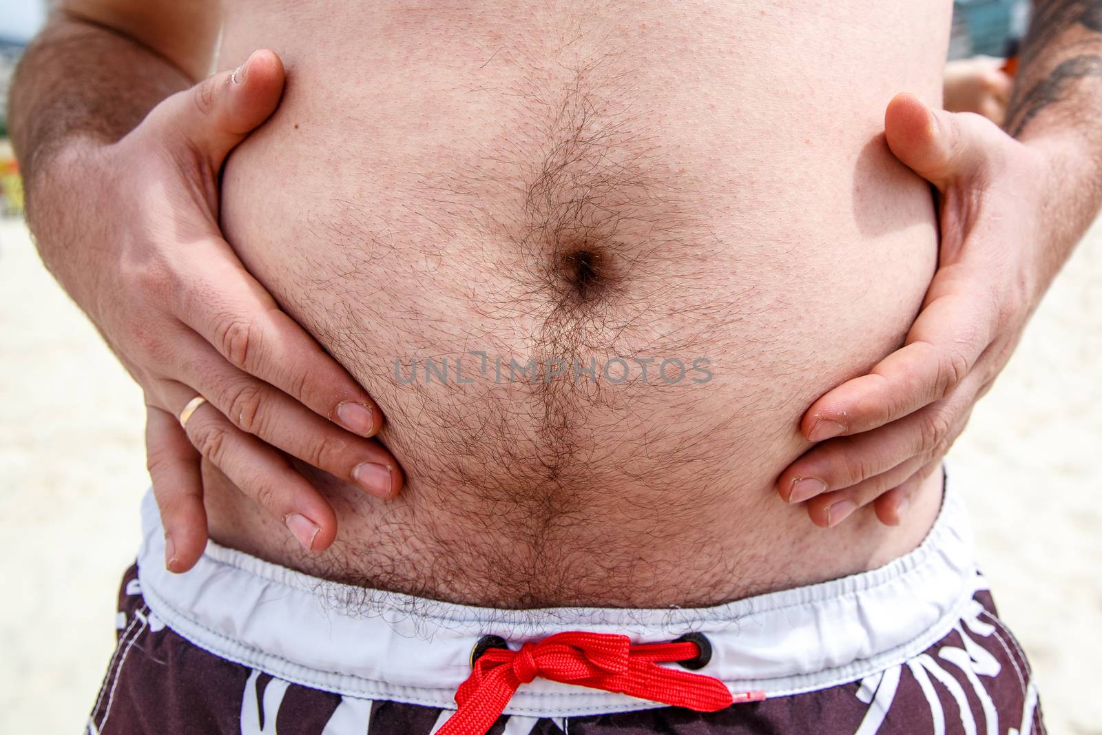 Close up of an obese fat man showing his belly on the beach. by 9parusnikov