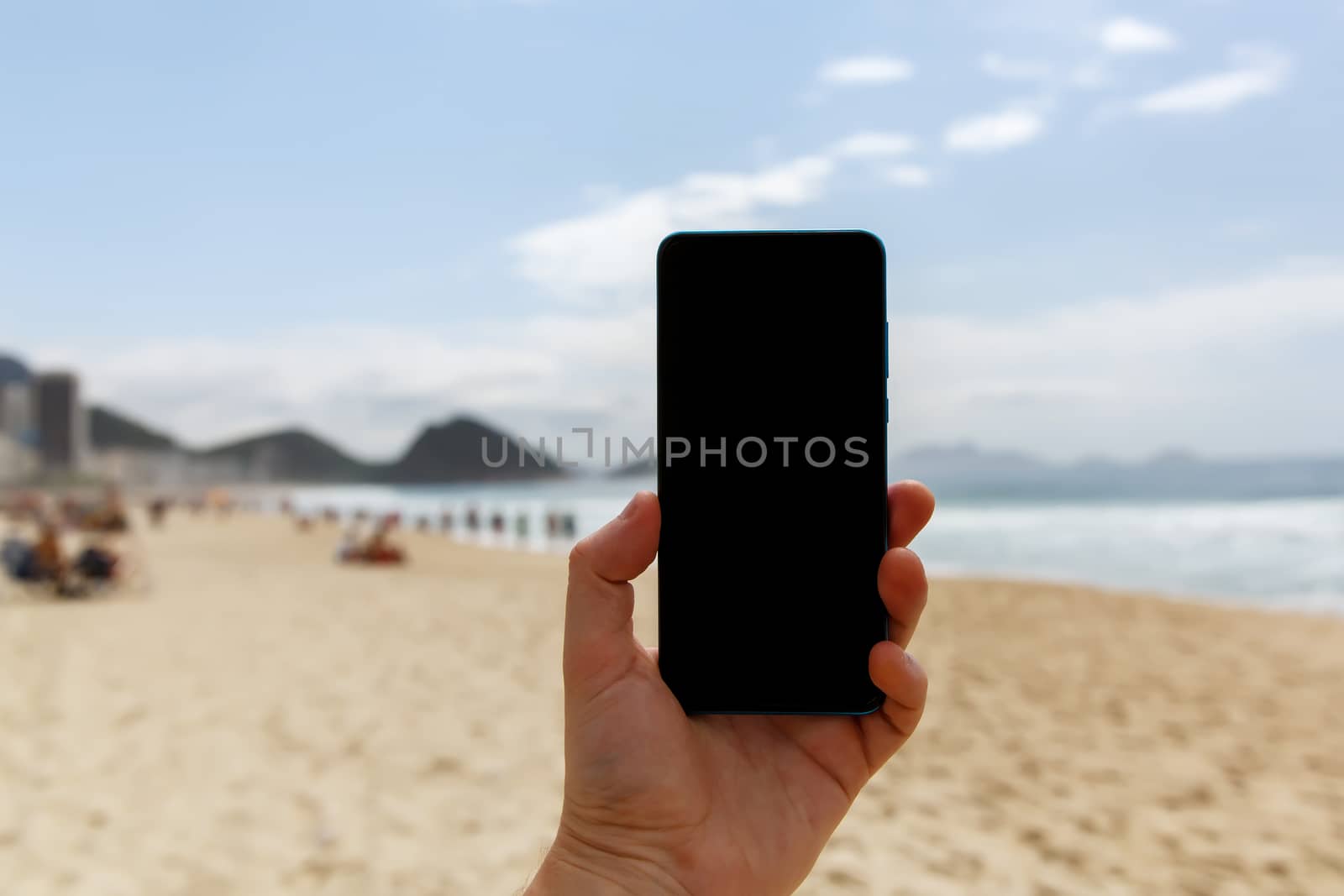 Using a smartphone on the beach. Blank black screen for your content