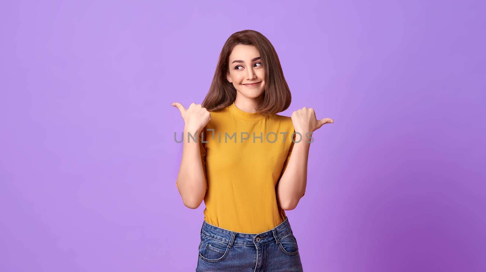 Happy young woman her pointing hand over purple banner background with copy space.