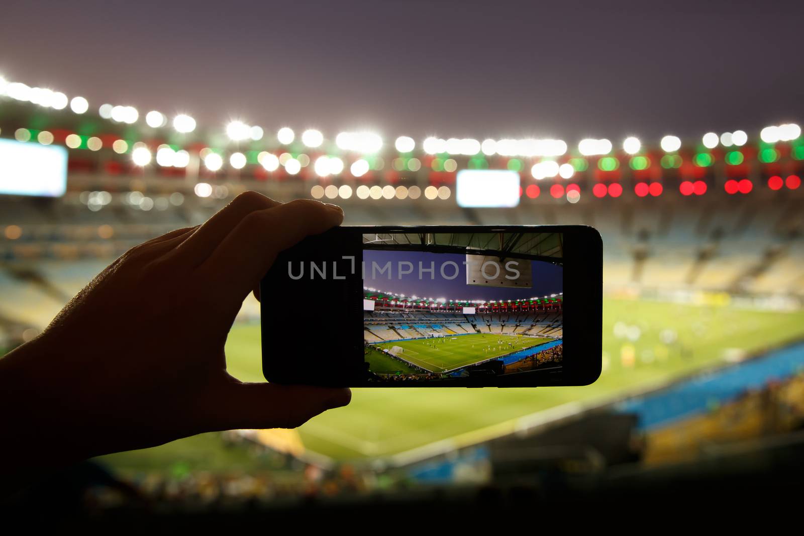 Smartphone photographing football game on the stadium.