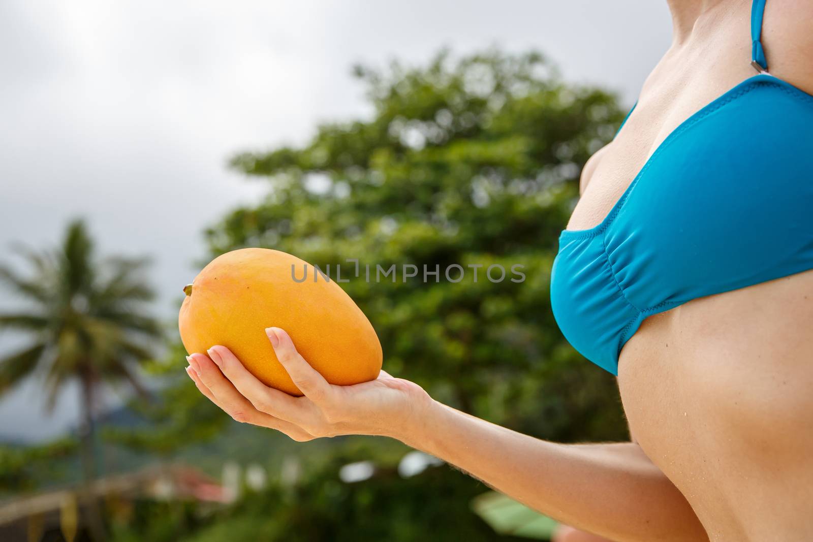 Girl with mango in hands on the ocean