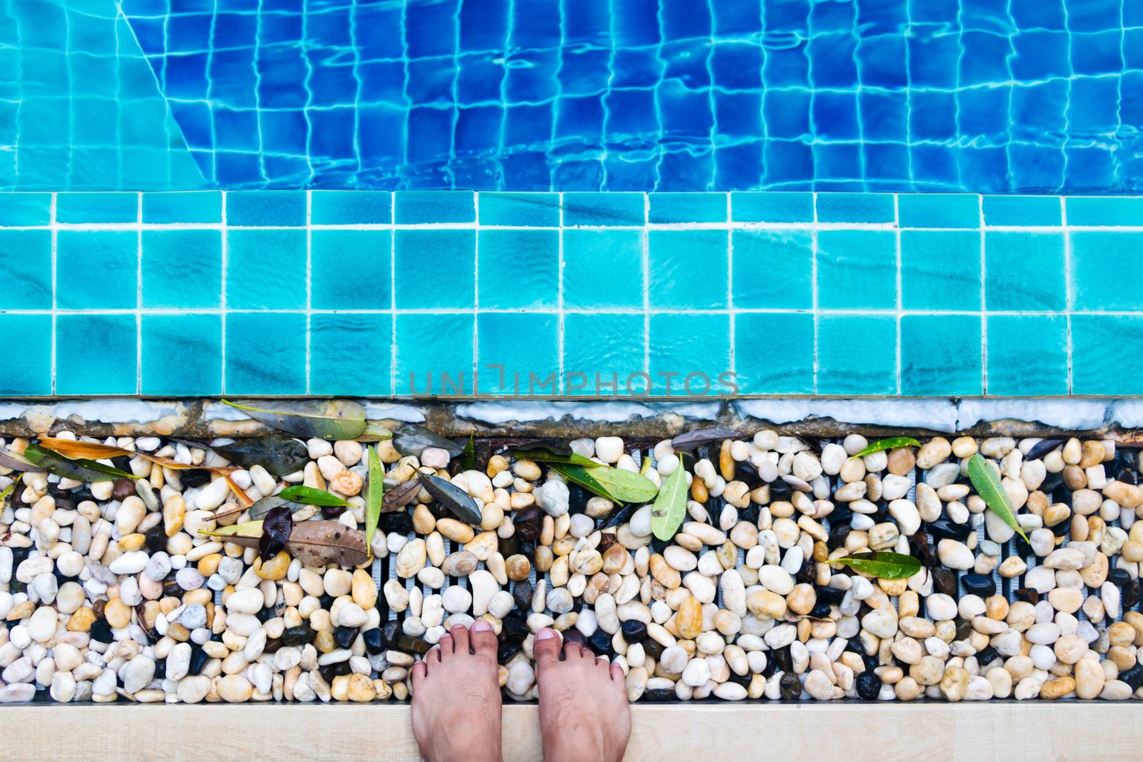 Asian man's feet standing by the pool by minamija