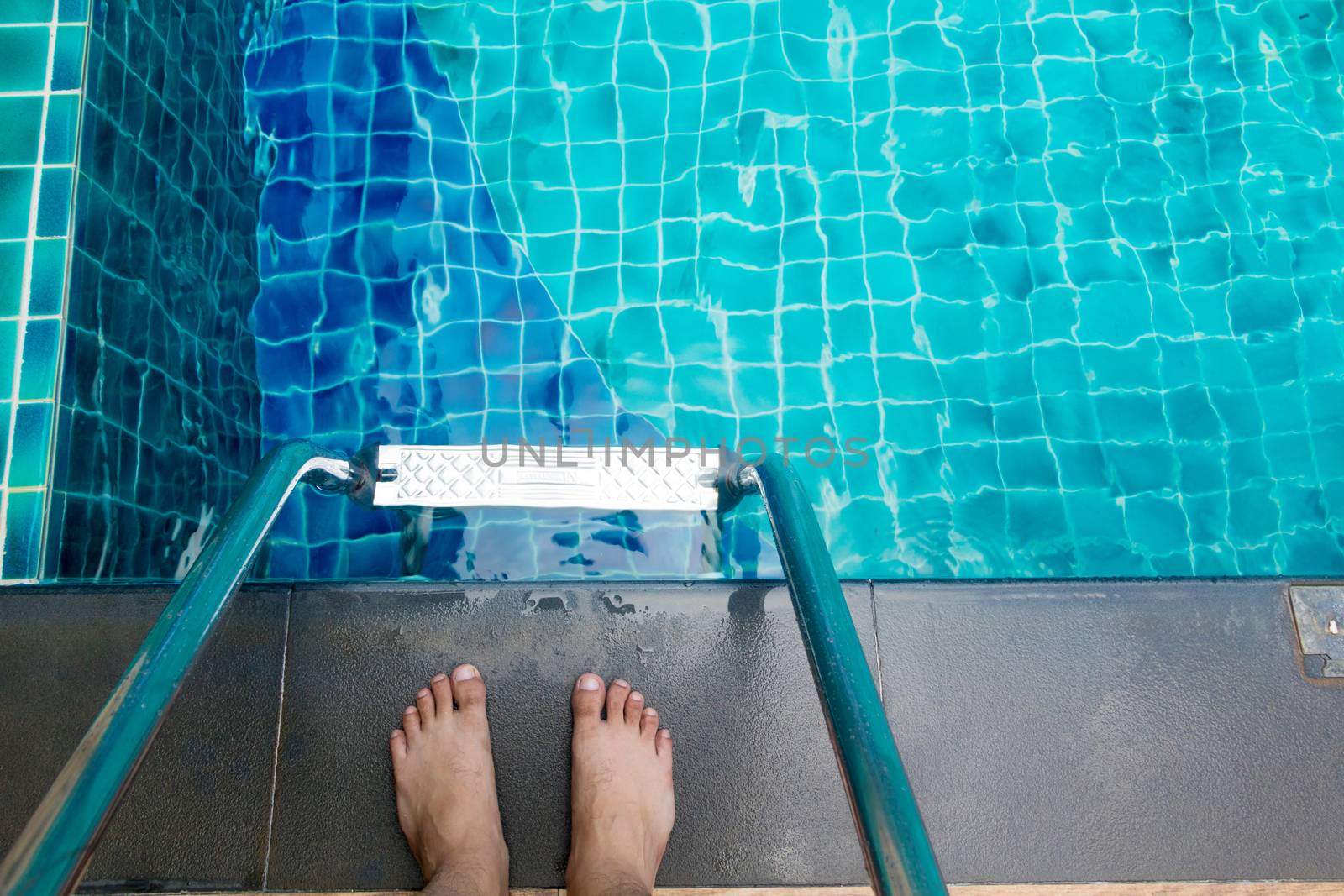 The feet of an Asian man standing at the edge of the pool To swim in the pool