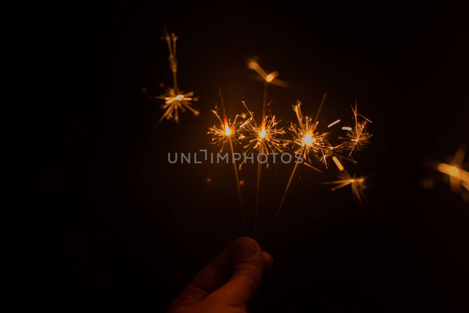 Hand holding sparklers in dark by rushay