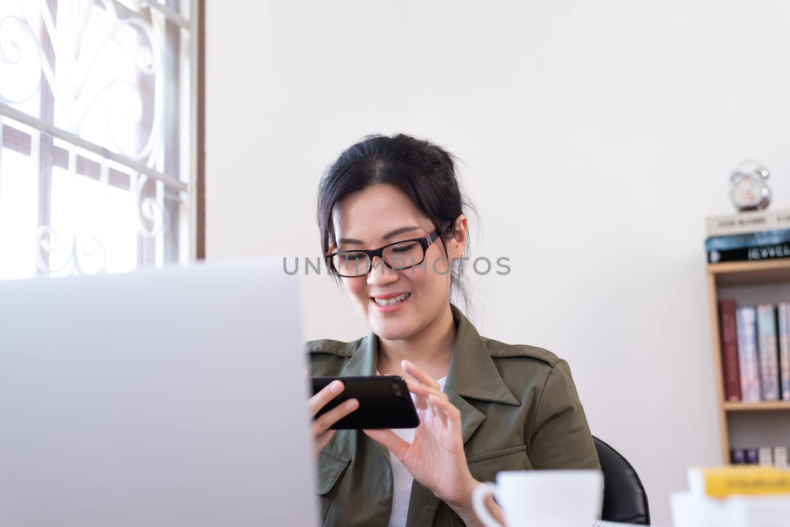 Modern young Asian woman playing a game instead of working from home with happy and fun.