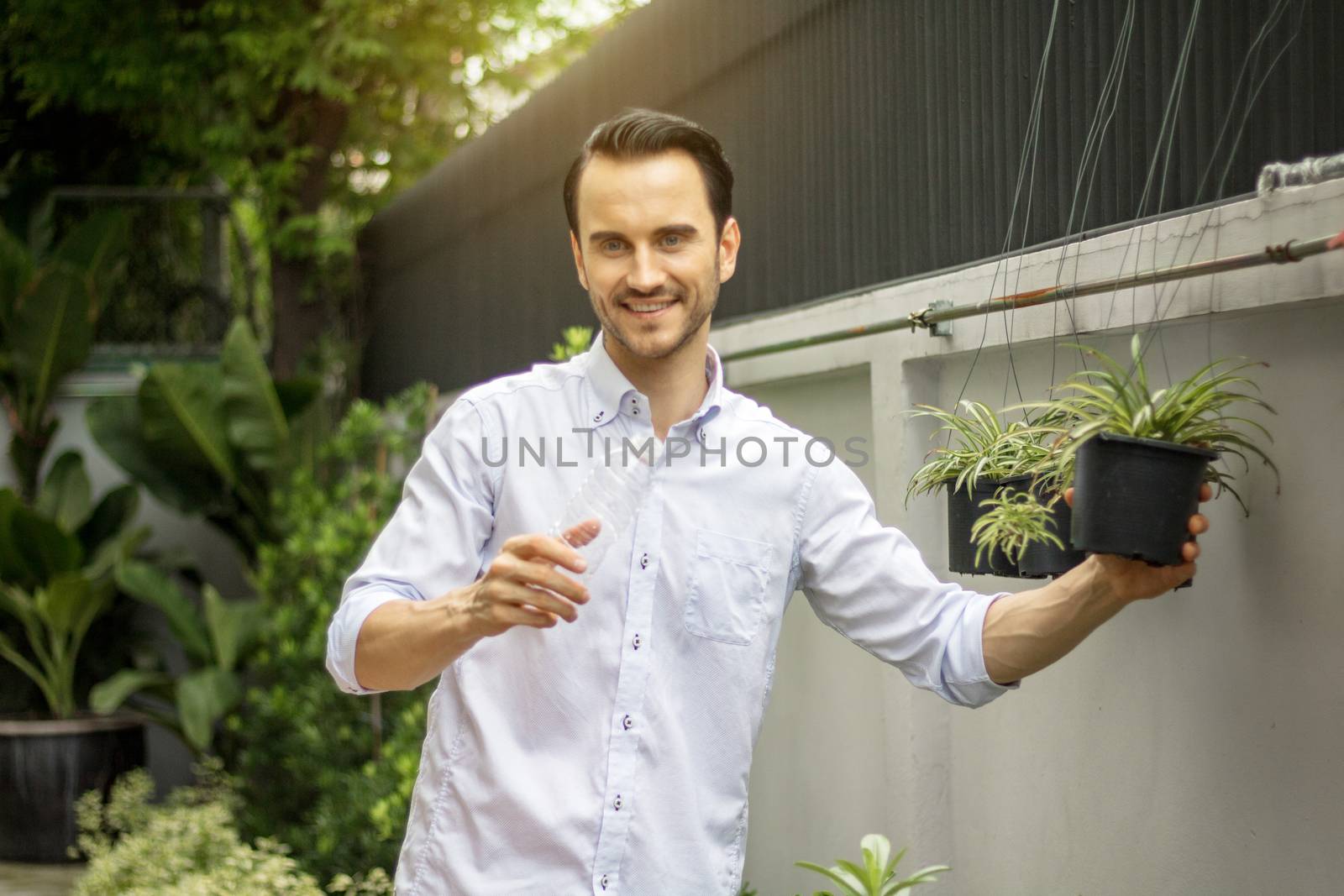 Young men watering plants in potted plants With recyclable plastic bottles. Recycle concept
