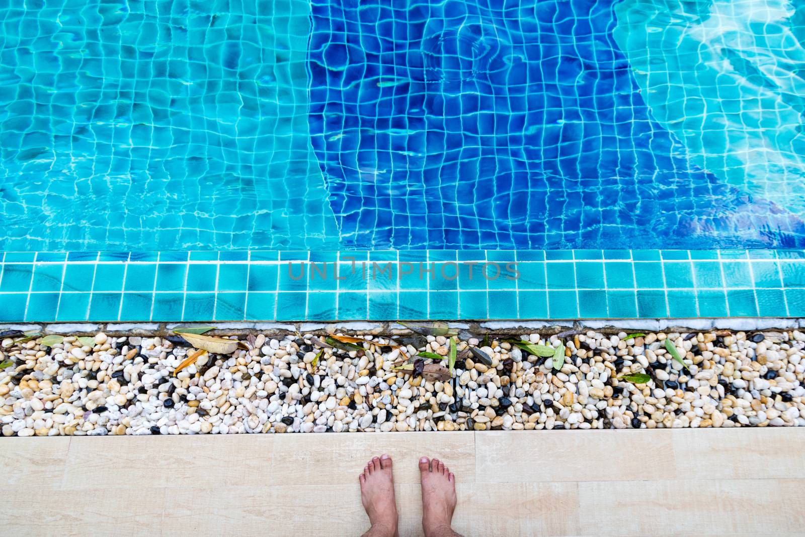 Asian man's feet standing by the pool by minamija