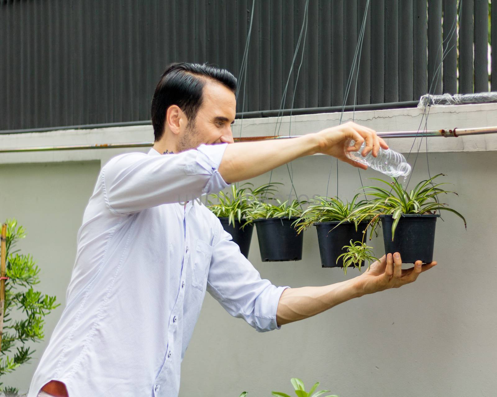 Young men watering plants in potted plants With recyclable plastic bottles When watering the plants, he twisted the plastic bottles to recycle.Young man working in the garden.