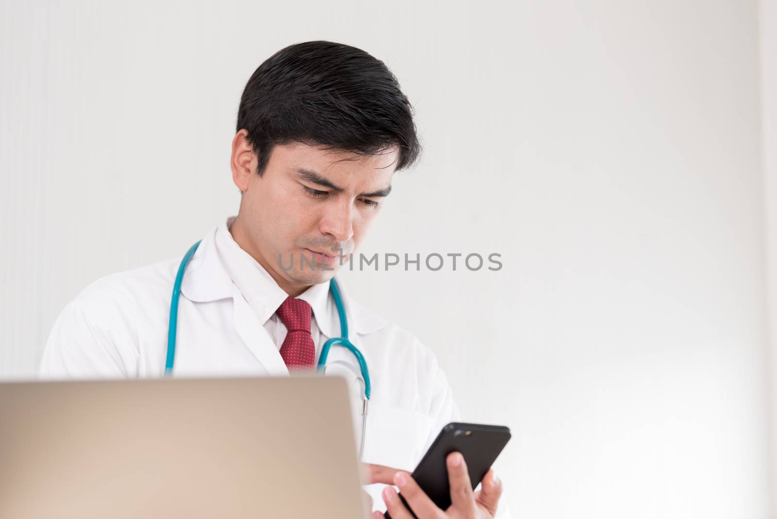 A doctor woman has to work with a mobile phone at the hospital. by animagesdesign