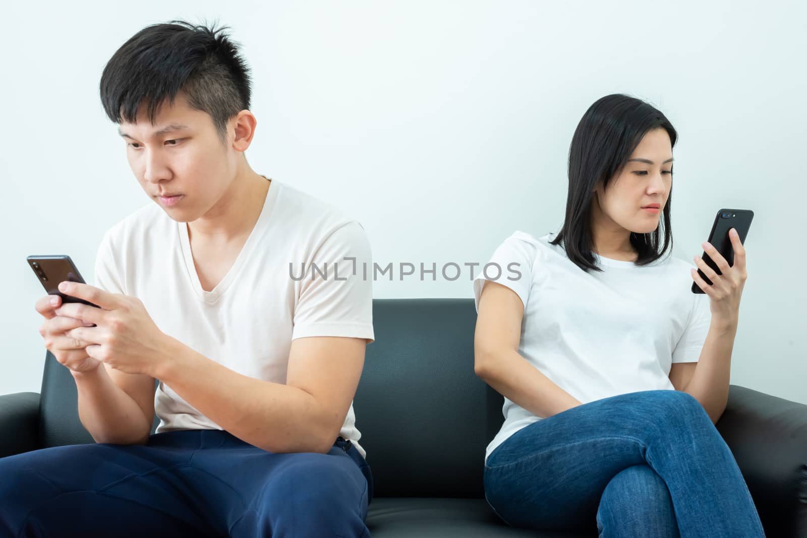 An Asian couple stays together and playing the phone with social distancing.