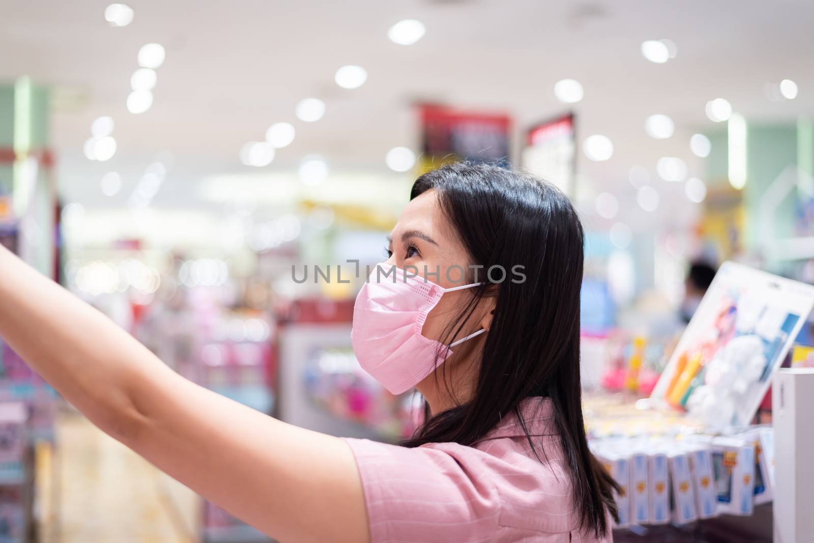 An Asian woman shopping in the toy shop after opening lockdown with pink mask and social distancing.