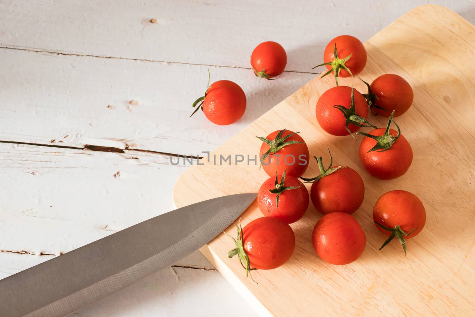 Red tomato on a cutting board wiht wooden background. by Khankeawsanan
