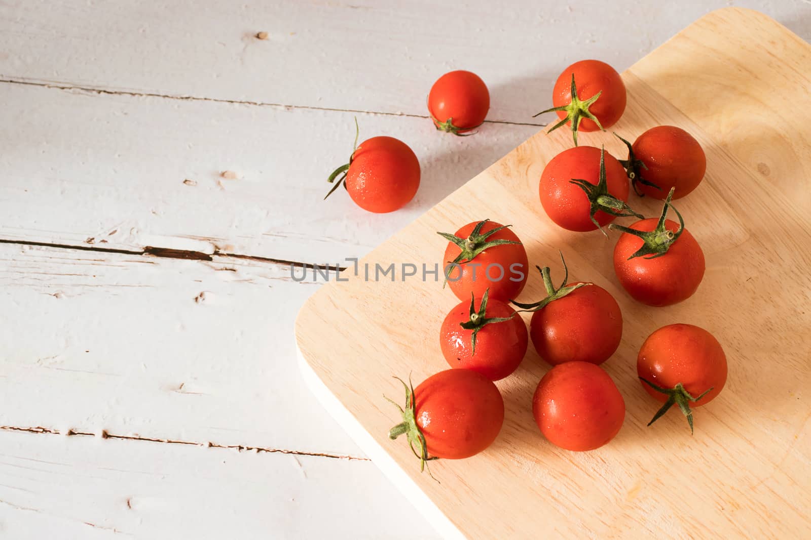 Red tomato on a cutting board wiht wooden background.