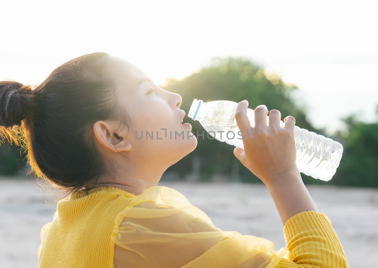 Asian woman drinking pure water from plastic bottle with light in the morning, Selective focus